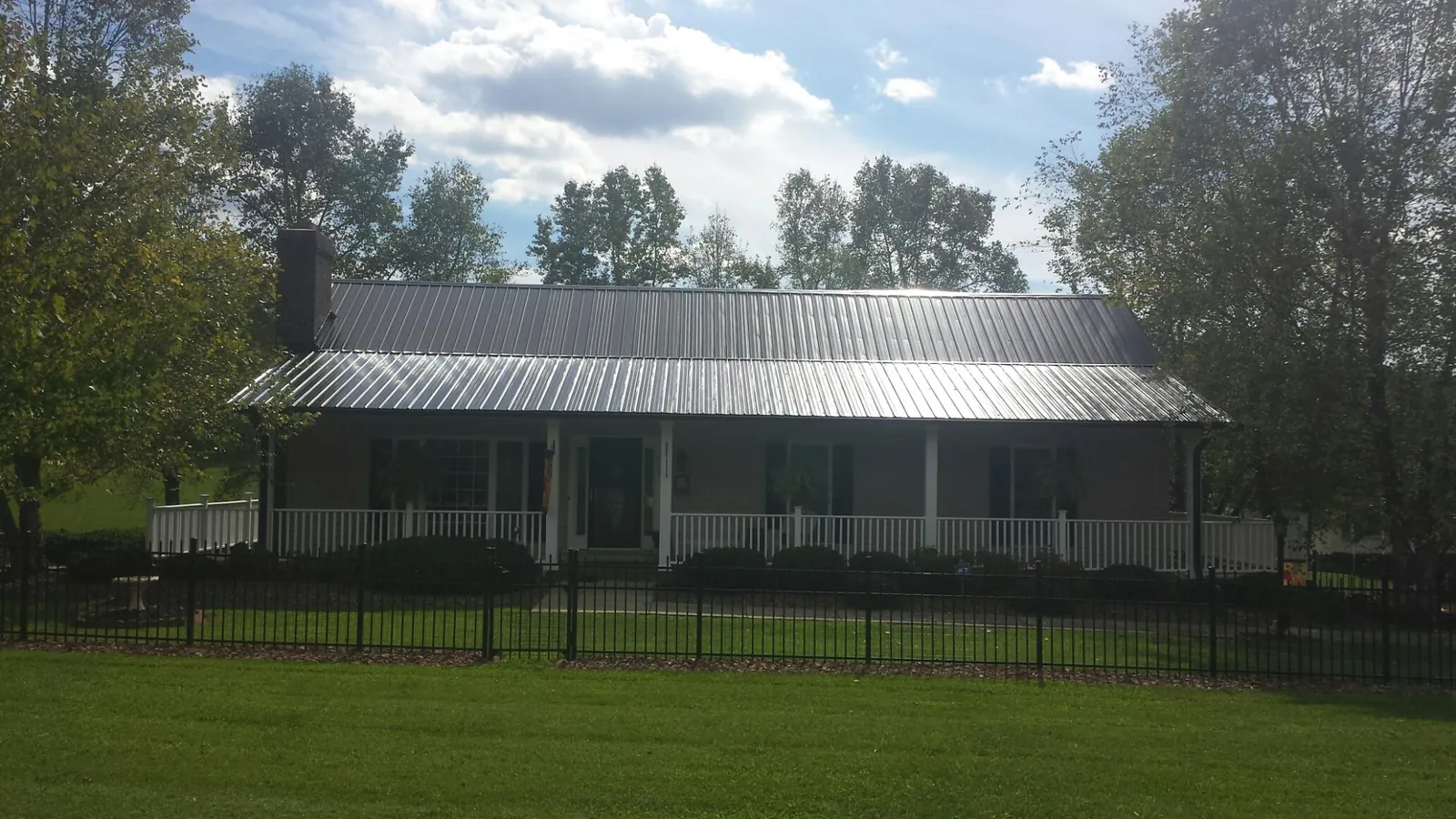 Gray metal roof on a brick ranch with a full width front porch — Gutter Guard Installation work by our crew in Genesee
